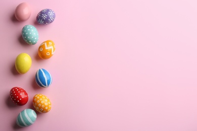 Photo of Flat lay composition of painted Easter eggs on color background, space for text