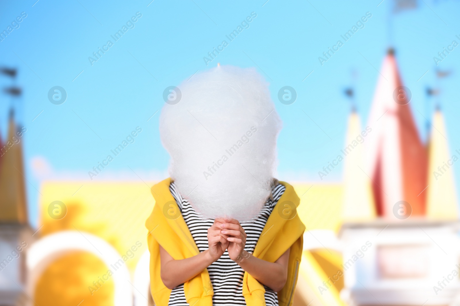 Photo of Young woman having fun with cotton candy in amusement park