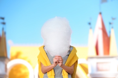 Photo of Young woman having fun with cotton candy in amusement park