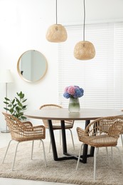 Table, chairs and vase of hydrangea flowers in dining room. Stylish interior