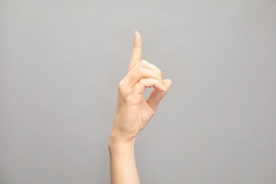 Woman showing D letter on grey background, closeup. Sign language