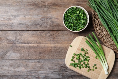 Photo of Flat lay composition with fresh green onions on wooden background. Space for text