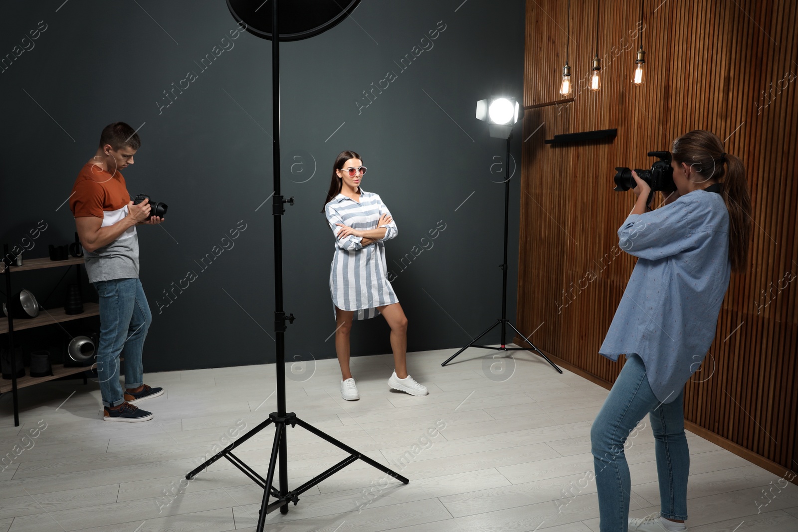 Photo of Professional photographer with assistant taking picture of young man in modern studio