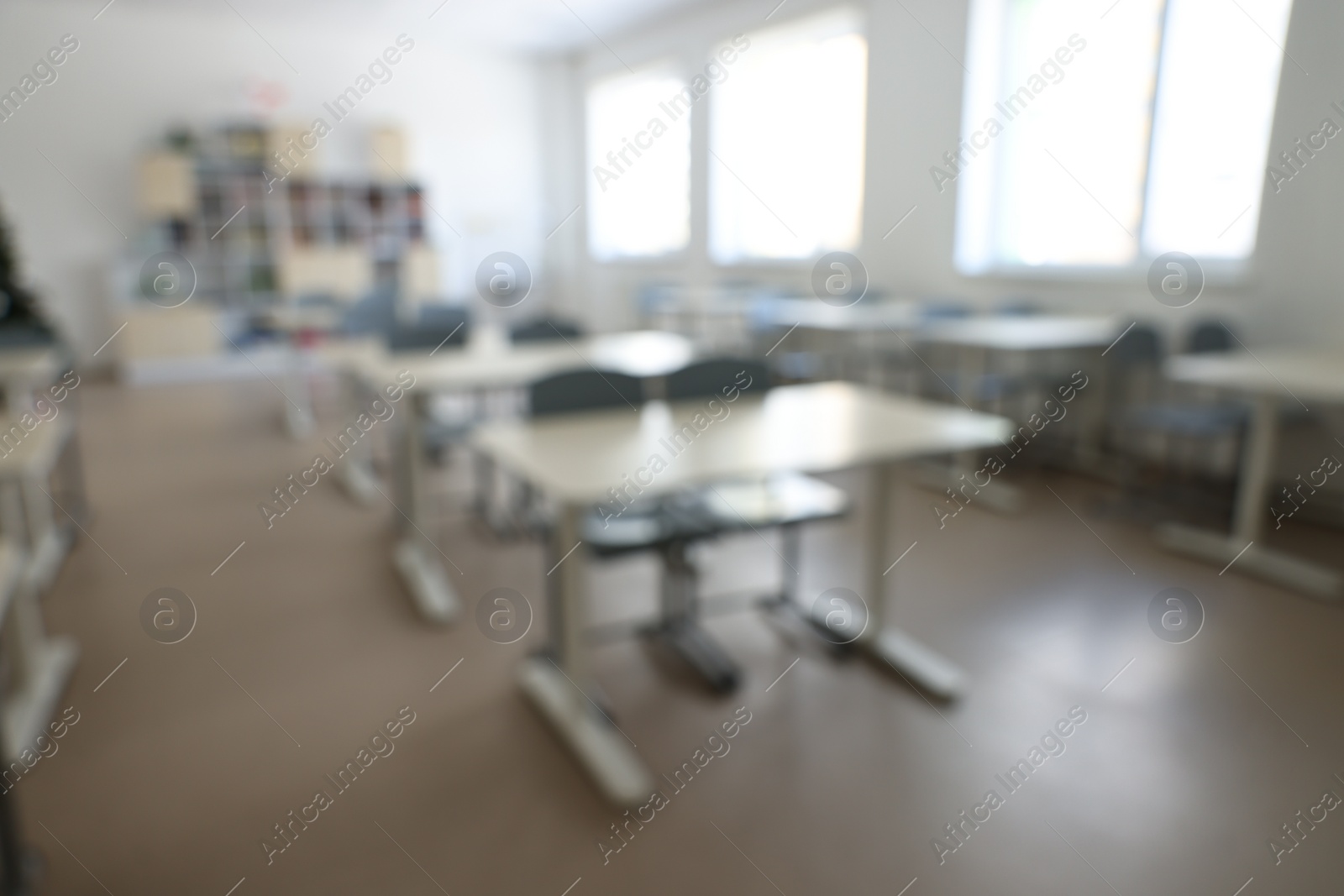 Photo of Blurred view of empty school classroom with desks, windows and chairs