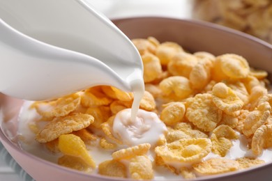 Photo of Pouring milk into bowl with cornflakes, closeup