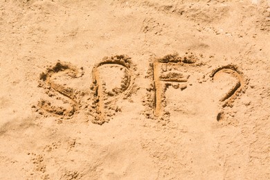 Photo of Abbreviation SPF and question mark written on sand at beach, above view