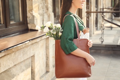 Woman with leather shopper bag near building, closeup