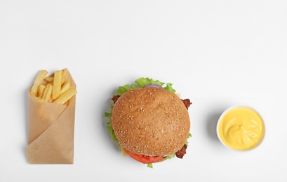 Tasty burger, french fries and sauce on white background, top view