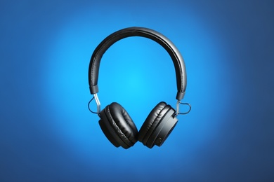 Stylish headphones with pads on color background