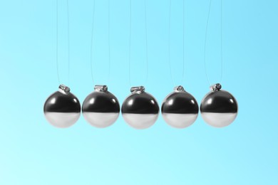Photo of Newton's cradle on light blue background. Physics law of energy conservation
