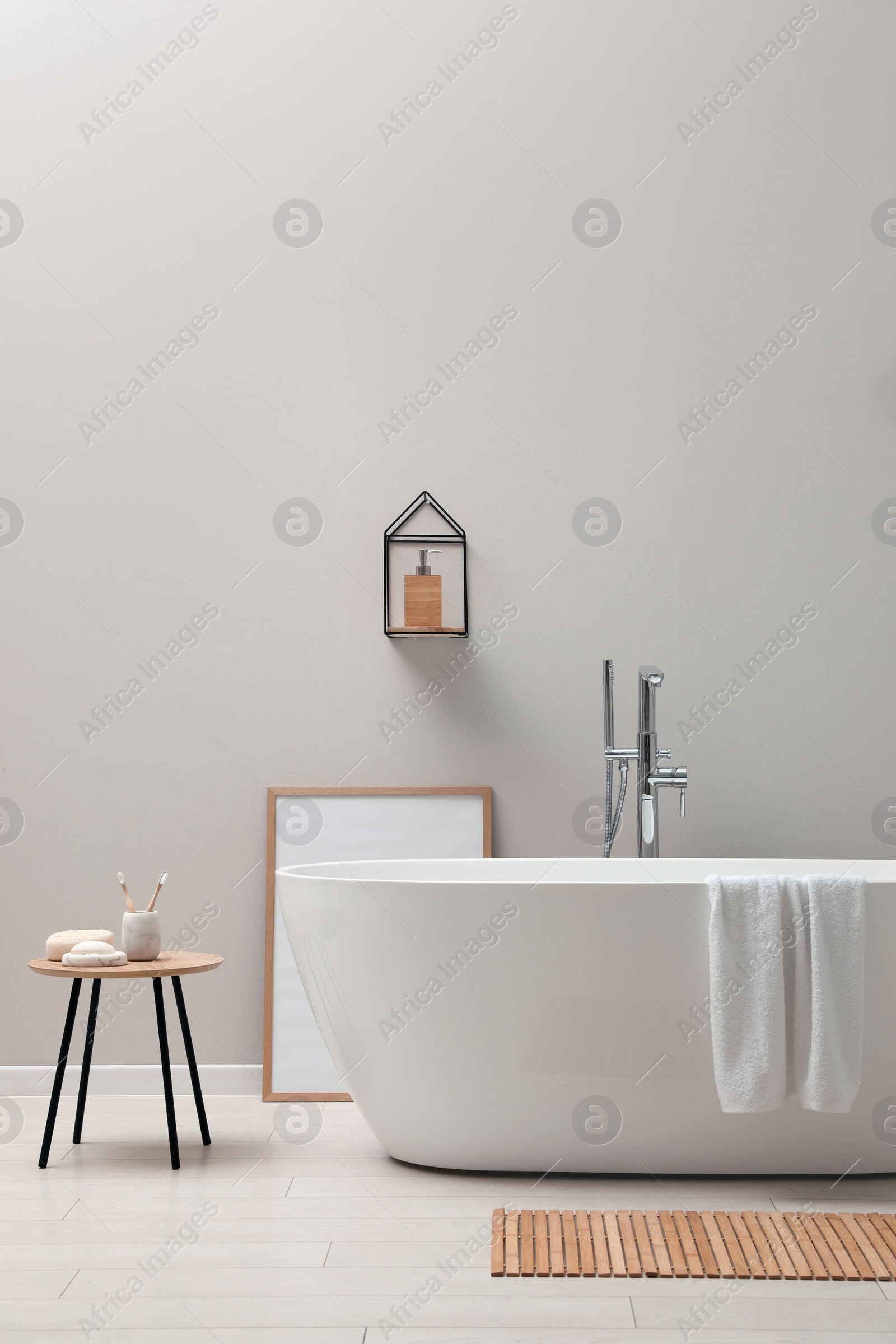 Photo of Modern ceramic bathtub near light wall indoors