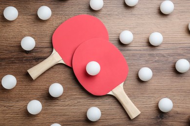 Photo of Ping pong rackets and balls on wooden table, flat lay