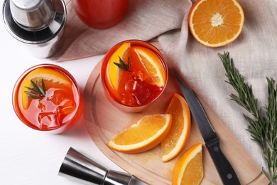 Photo of Aperol spritz cocktail, rosemary and orange slices on white wooden table, flat lay