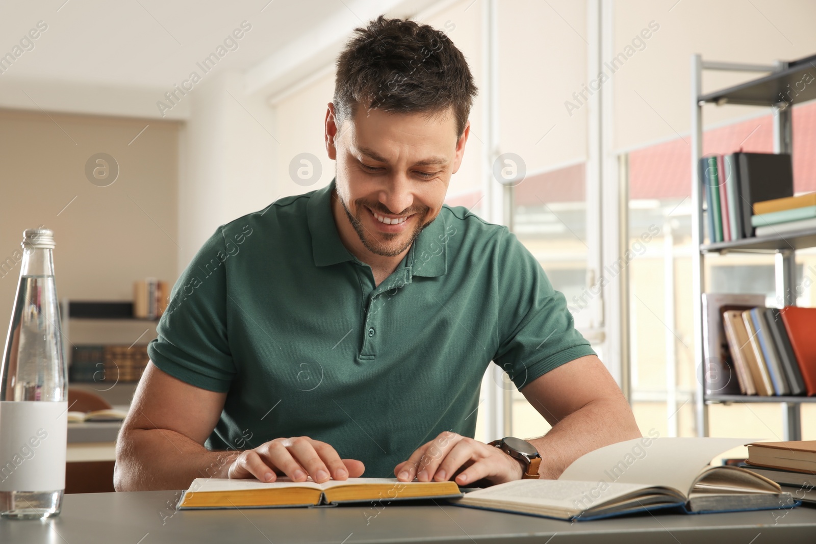 Photo of Man reading book at table in library