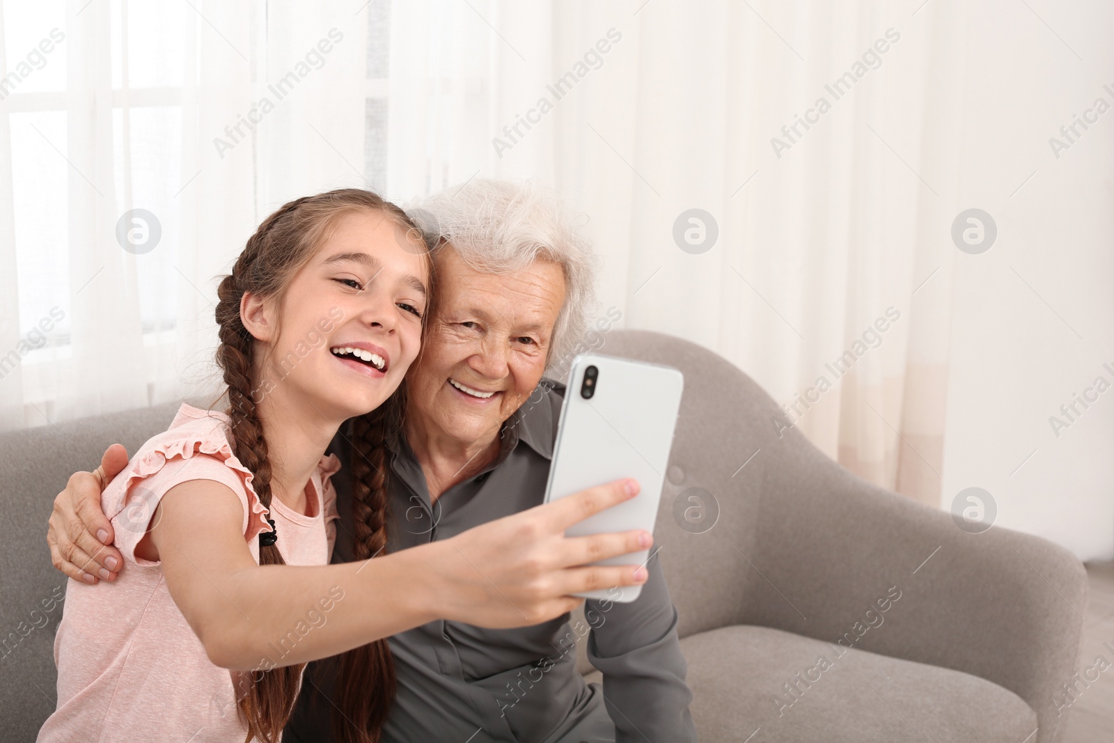 Photo of Happy cute girl taking selfie with her grandmother at home