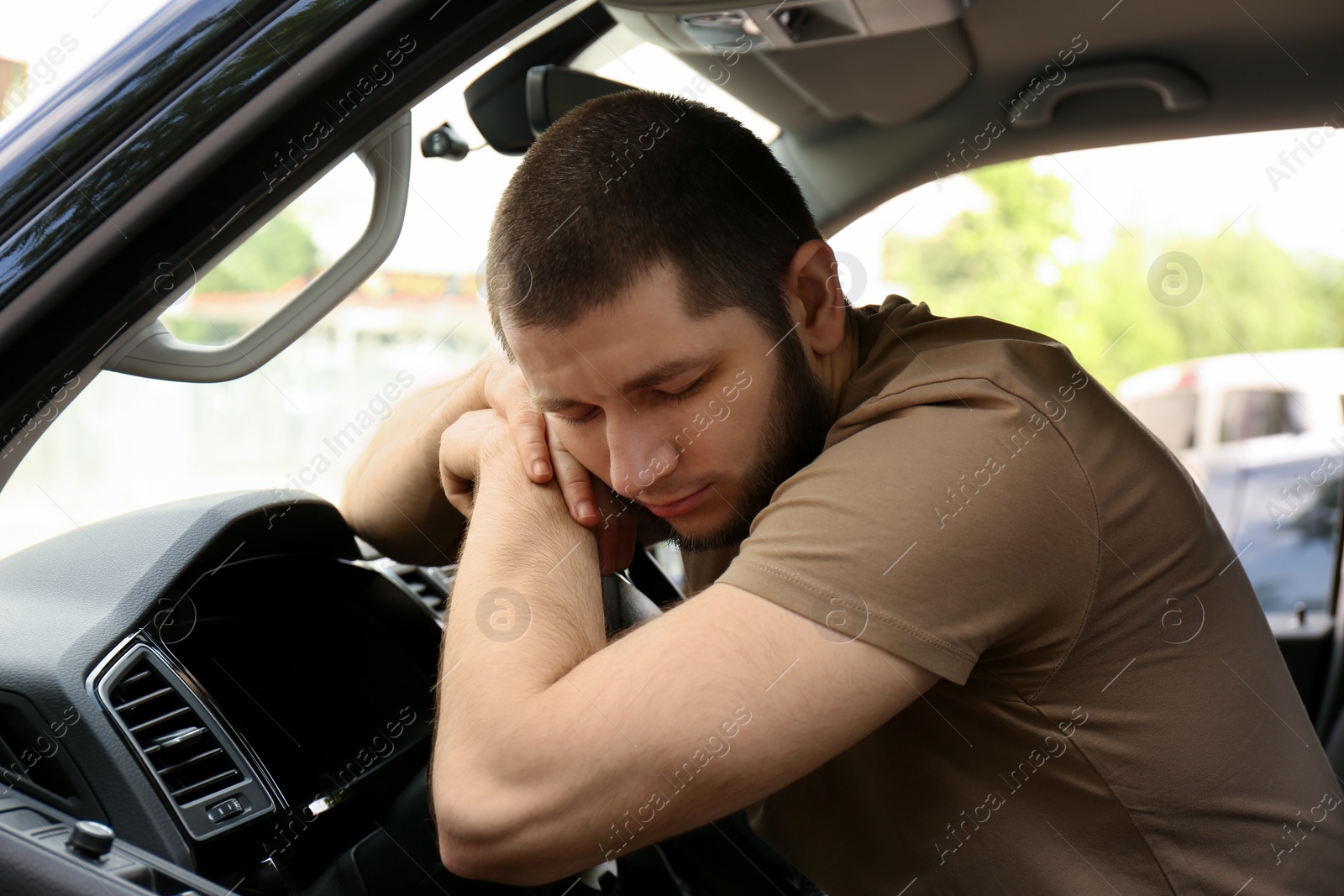 Photo of Tired man sleeping on steering wheel in his car