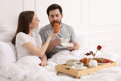 Photo of Tasty breakfast. Wife feeding her husband in bed at home. Space for text