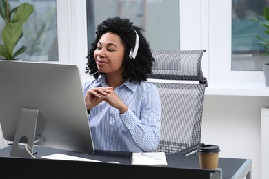 Young woman with headphones working on computer in office