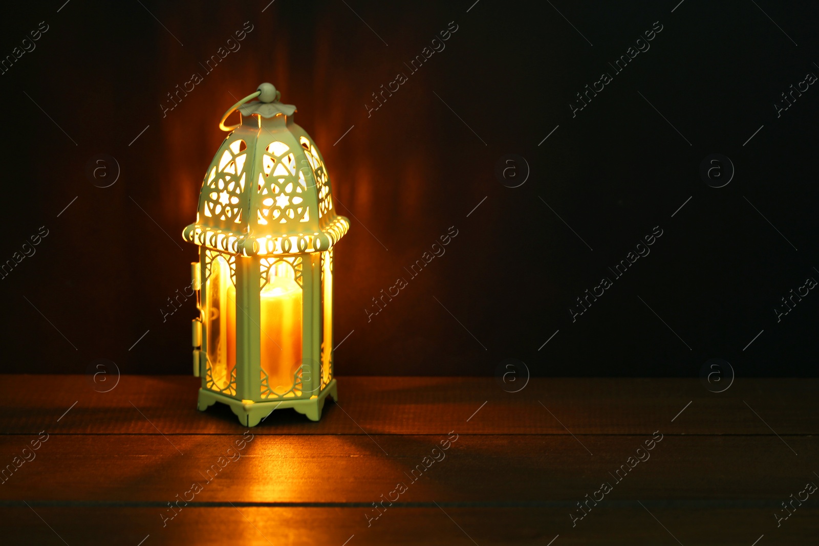 Photo of Decorative Arabic lantern on table against dark background. Space for text