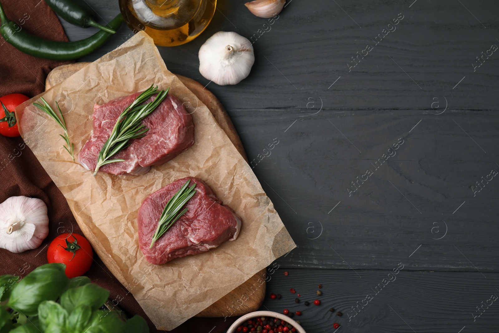 Photo of Flat lay composition with cut fresh beef meat on grey wooden table. Space for text