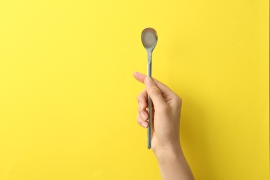 Photo of Woman holding empty soda spoon on color background, closeup. Space for text