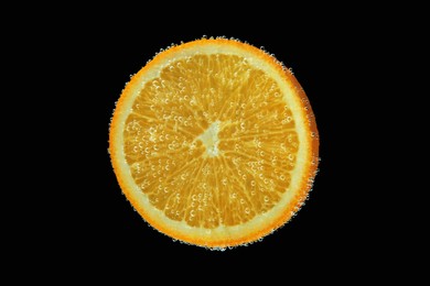 Slice of orange in sparkling water on black background. Citrus soda