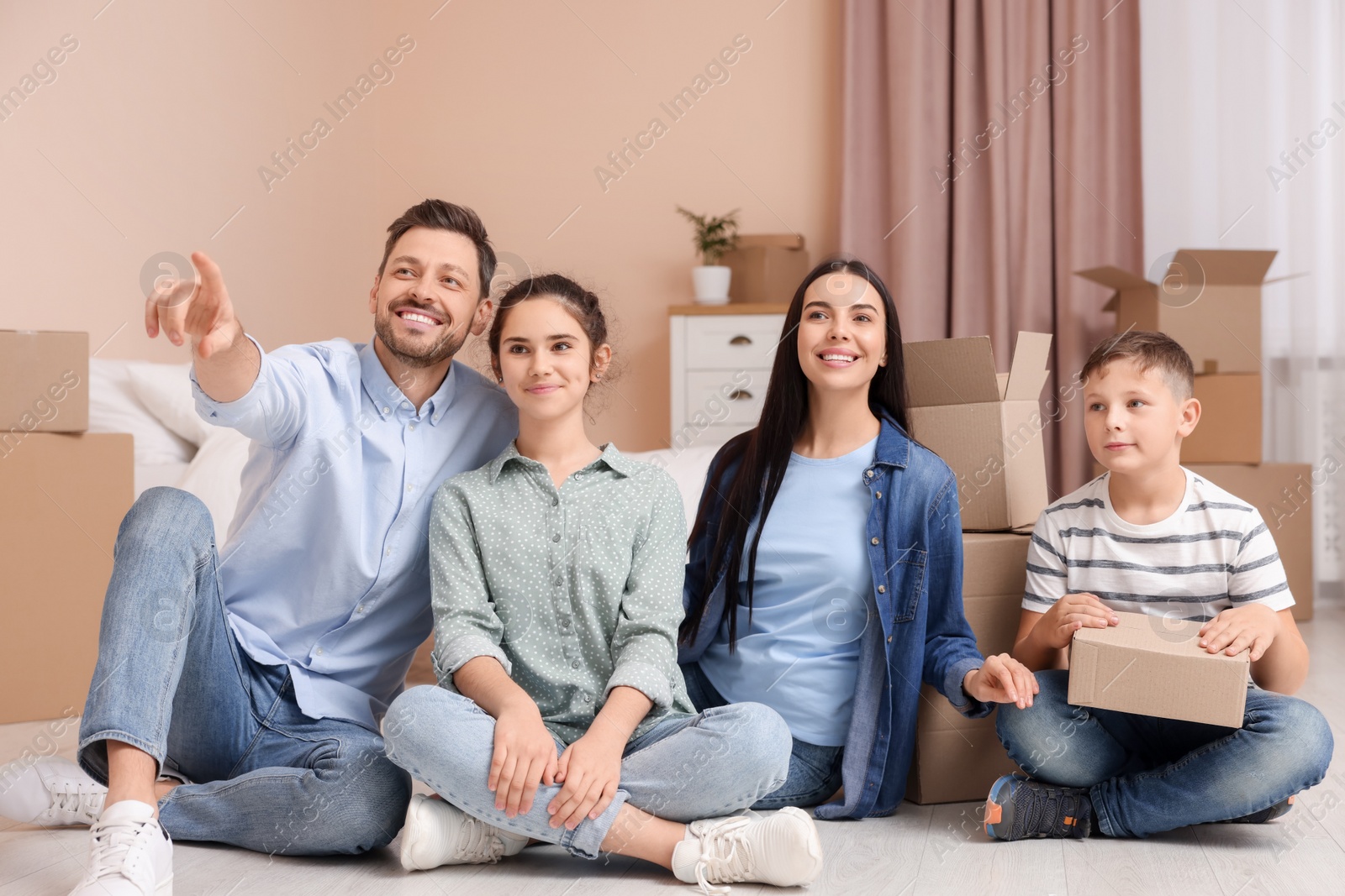 Photo of Happy family resting on floor near boxes in new apartment. Moving day