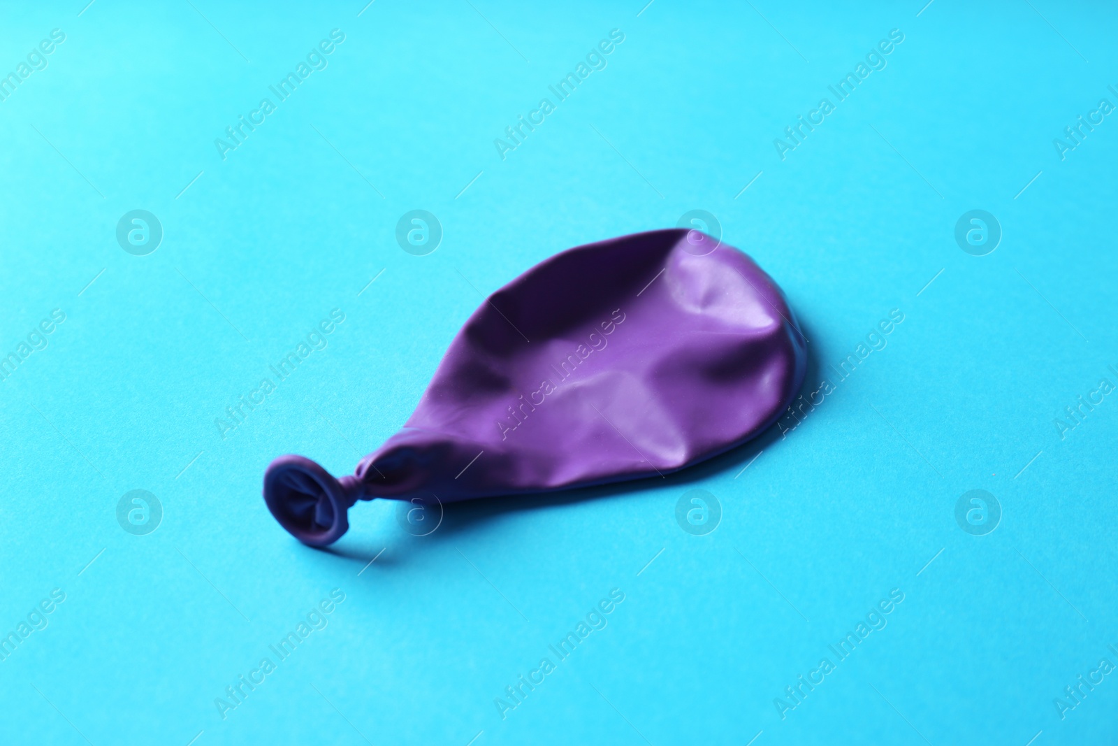 Photo of Purple deflated latex balloon on color background