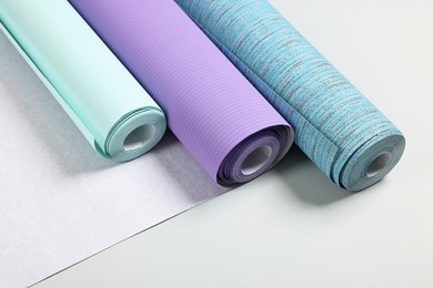 Different stylish wallpaper rolls on light background