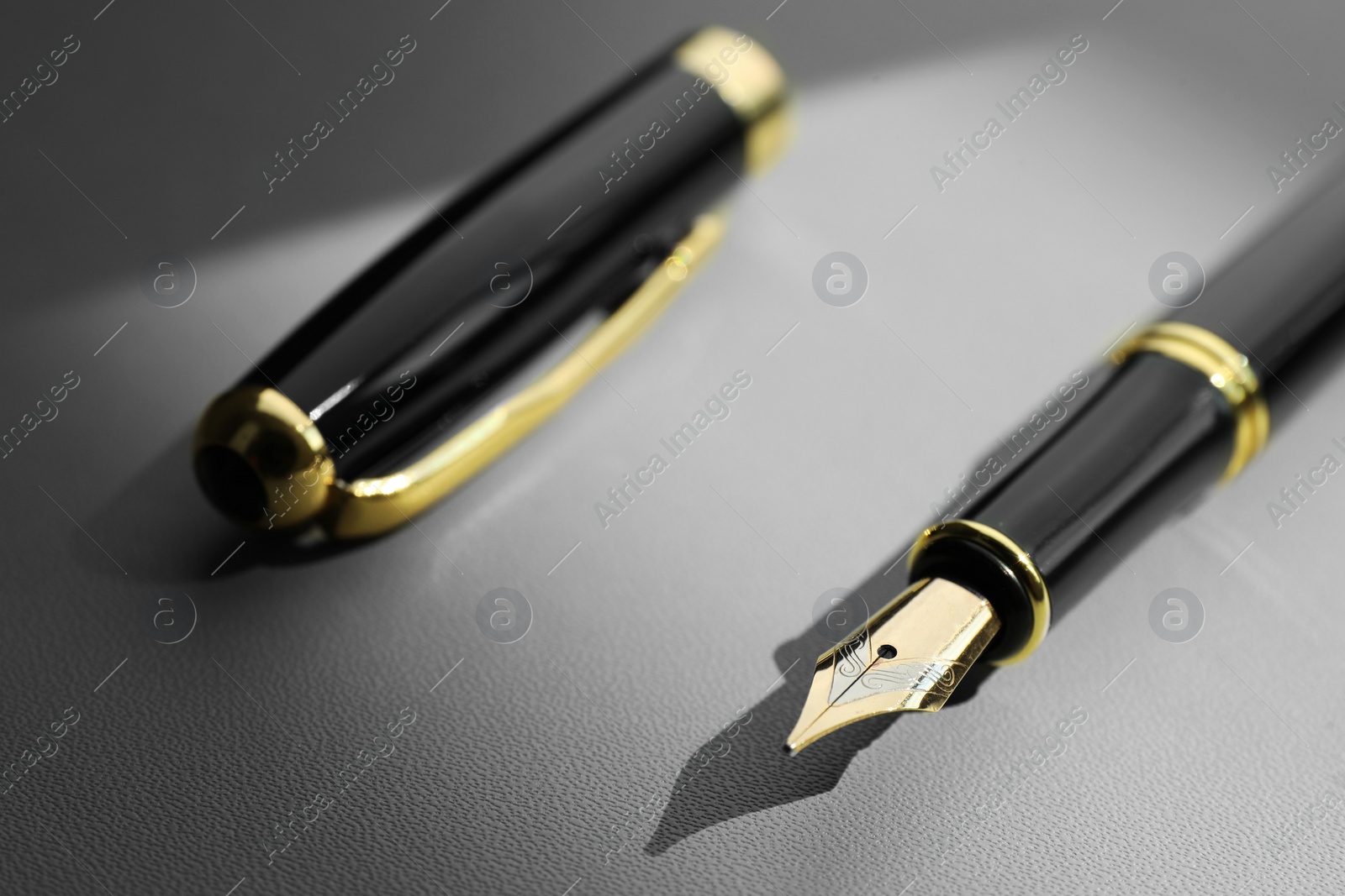 Photo of Stylish fountain pen on light grey textured table, closeup