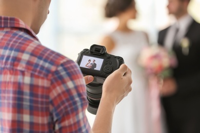 Professional photographer taking photo of wedding couple in studio