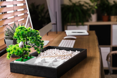 Photo of Modern workplace with beautiful miniature zen garden and computer in room
