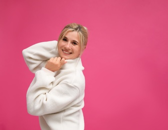 Photo of Happy woman in stylish sweater on pink background. Space for text