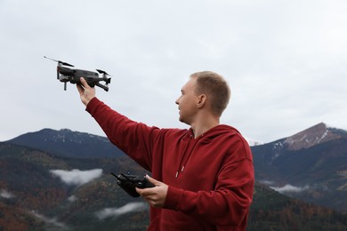 Photo of Young man with modern drone in mountains