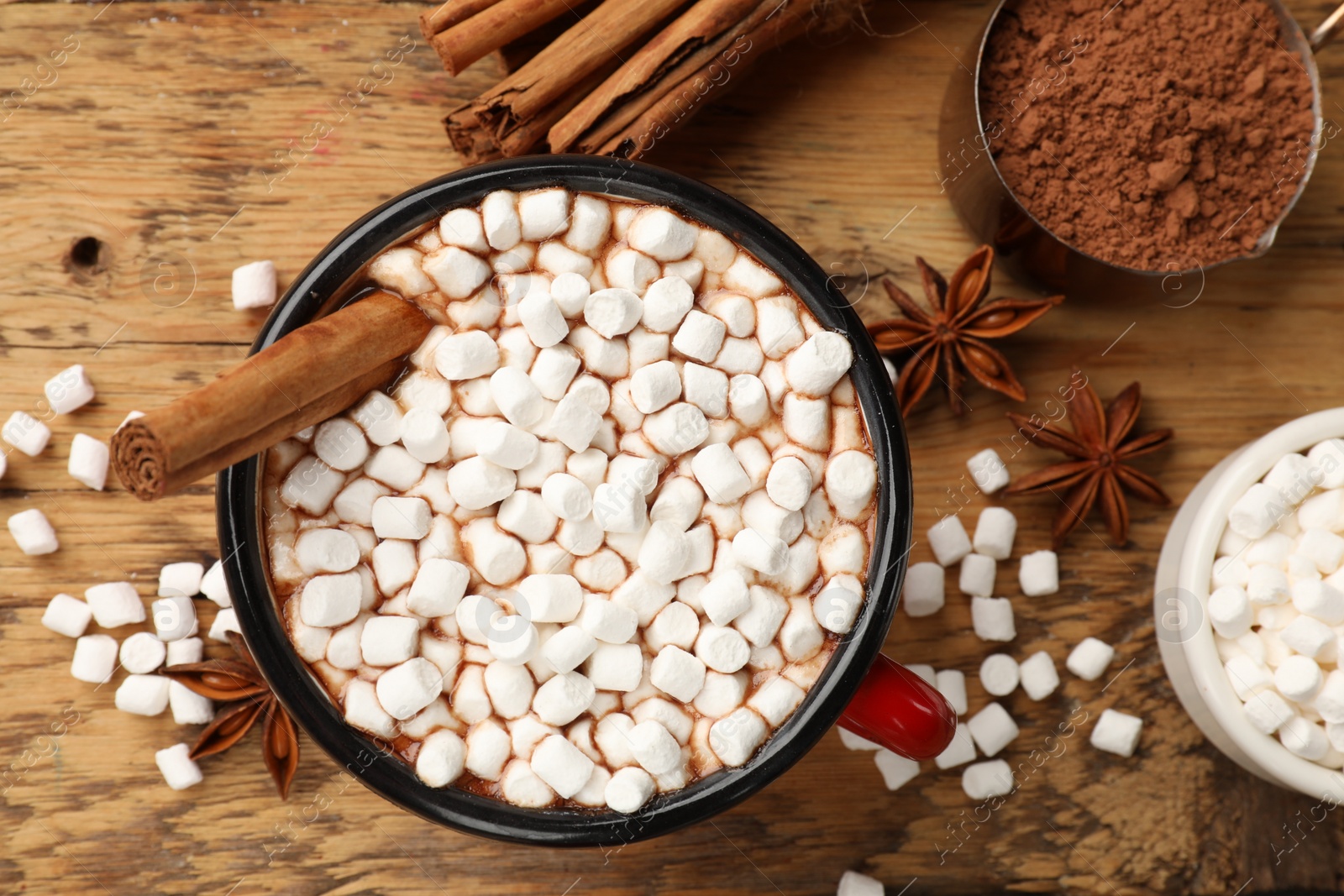 Photo of Tasty hot chocolate with marshmallows and ingredients on wooden table, flat lay