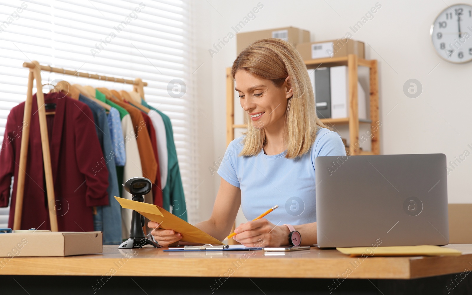 Photo of Seller with laptop and parcels working in office. Online store