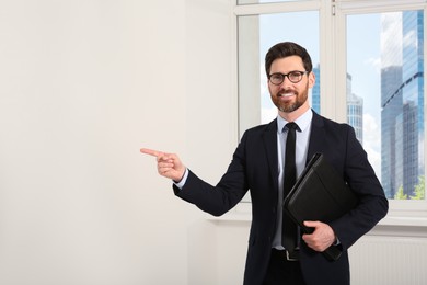 Photo of Handsome real estate agent with documents indoors, space for text