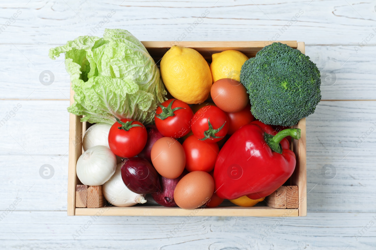 Photo of Wooden crate full of fresh products on light background, top view