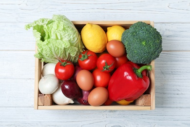 Photo of Wooden crate full of fresh products on light background, top view