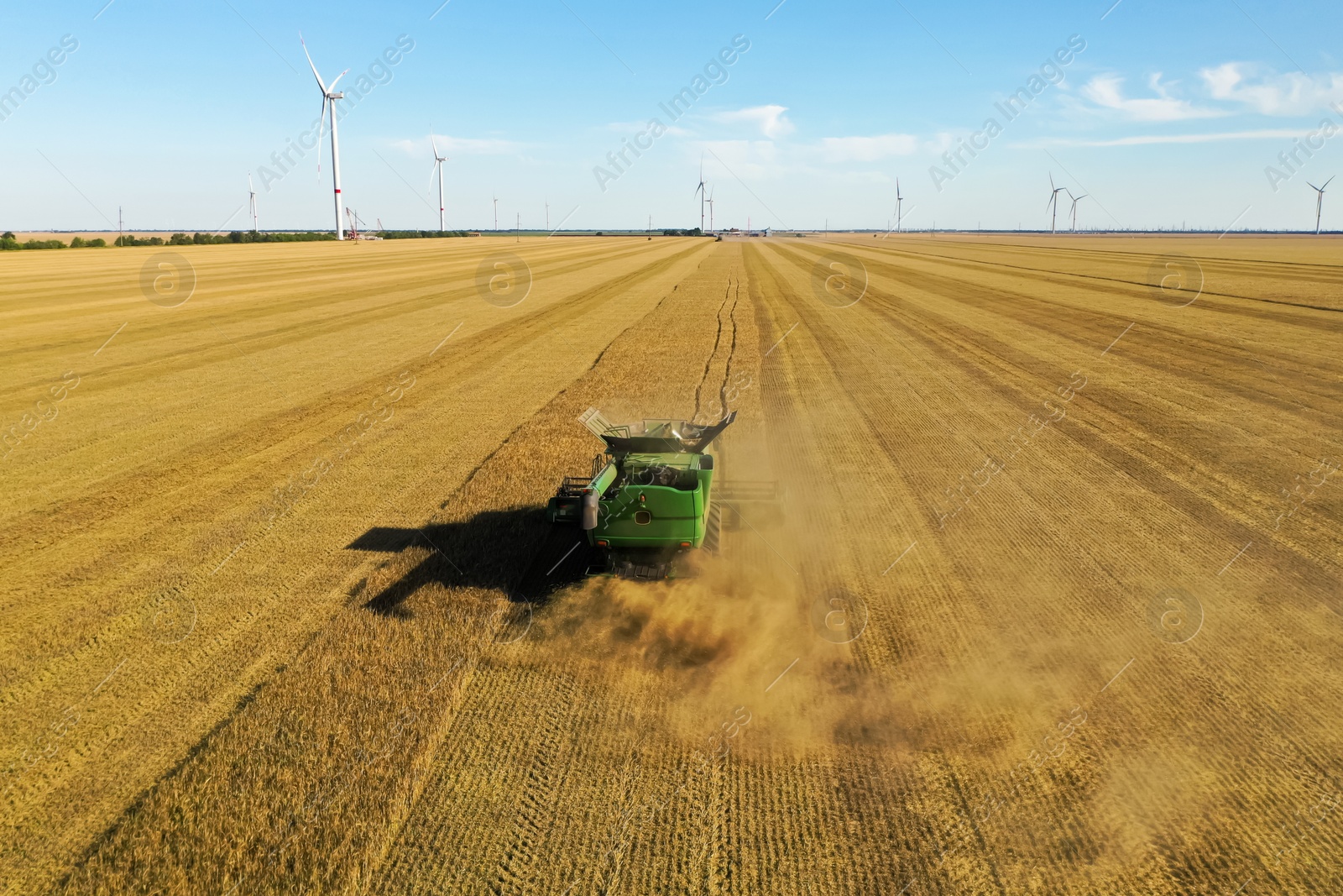 Photo of Modern combine harvester working in field on sunny day. Agriculture industry