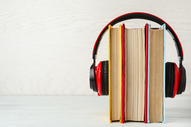 Books and modern headphones on white wooden table. Space for text