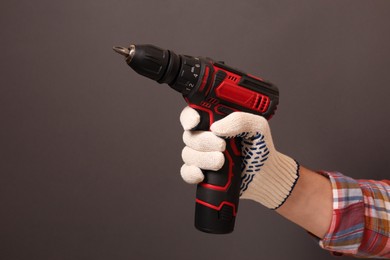 Photo of Handyman holding electric screwdriver on brown background, closeup