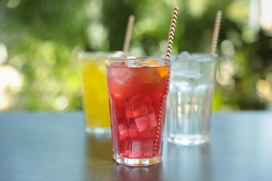 Photo of Delicious refreshing drinks in glasses on grey table outdoors