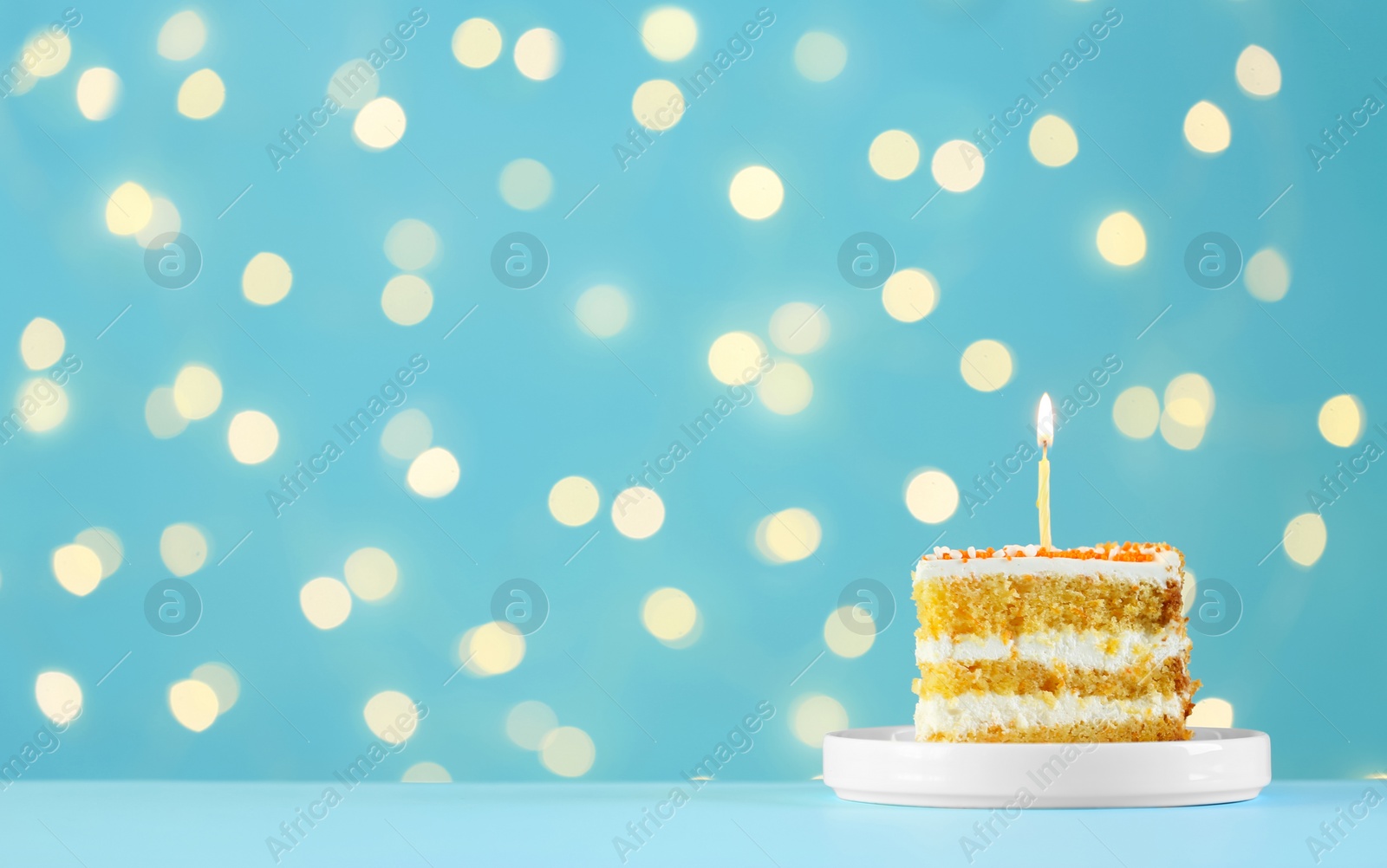Photo of Piece of delicious birthday cake with burning candle against blurred lights on turquoise background. Space for text
