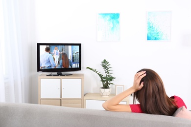 Photo of Young woman watching TV on sofa at home
