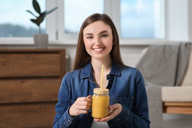 Beautiful young woman with delicious smoothie at home