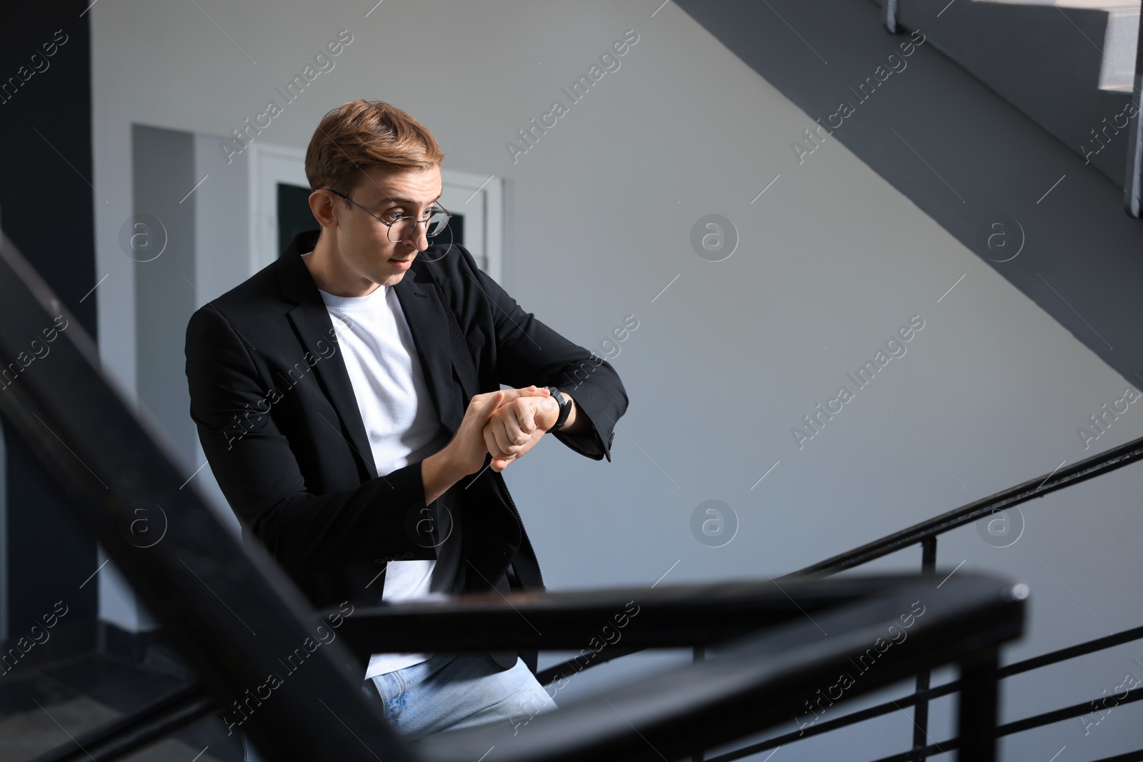 Photo of Emotional young man checking time in office. Being late