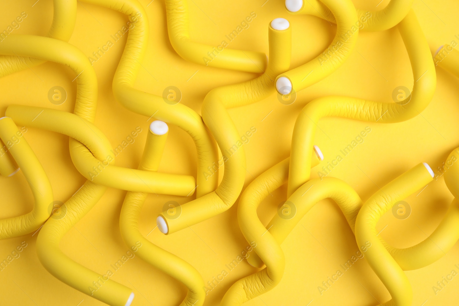 Photo of Curling rods on yellow background, flat lay. Hair styling tool