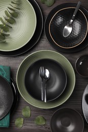 Photo of Stylish table setting with cutlery and eucalyptus branch on dark wooden background, flat lay