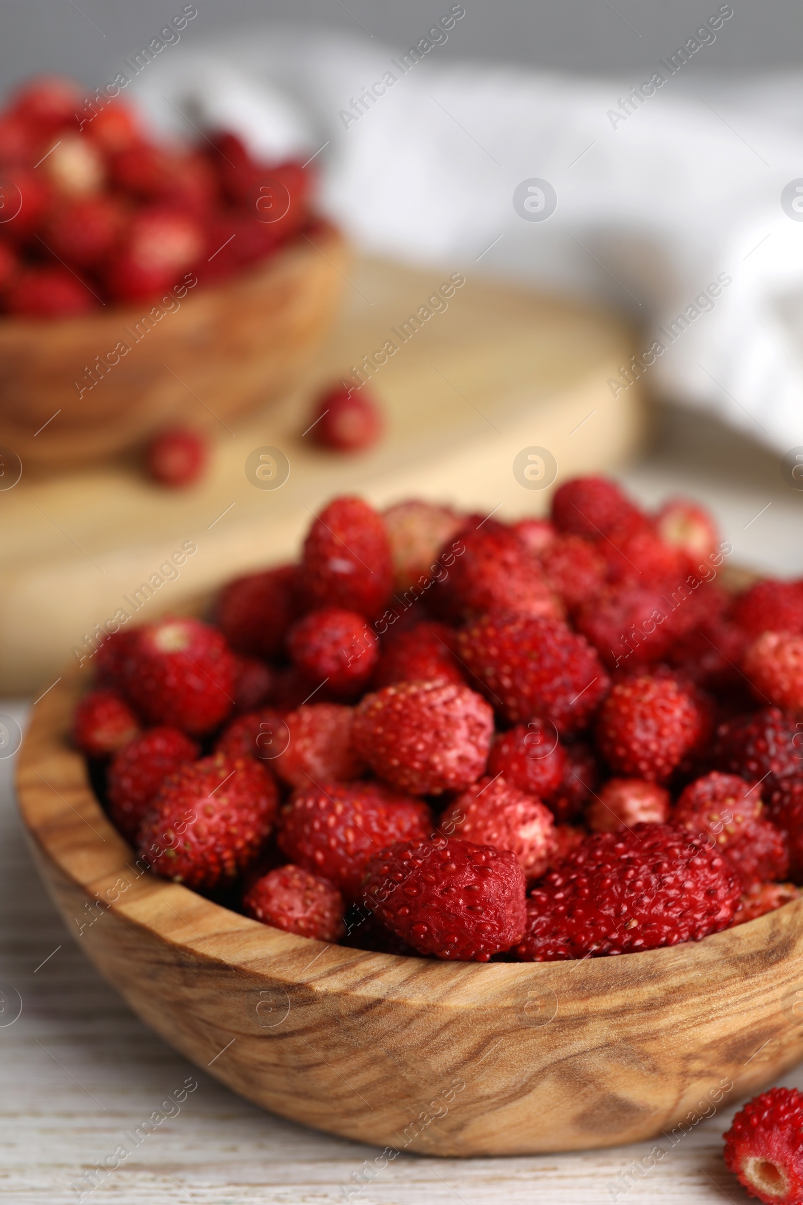 Photo of Fresh wild strawberries in bowl on white wooden table